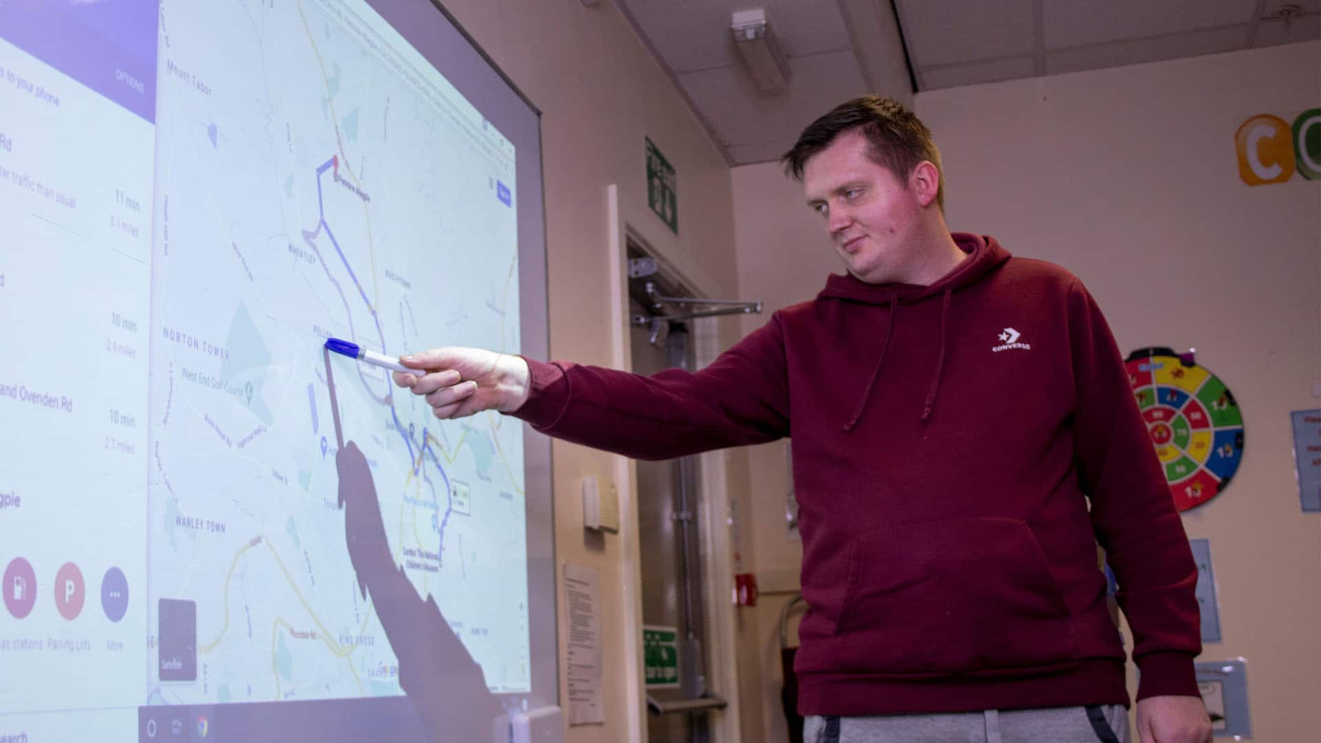 A service user pointing to a spot on a map projected onto a screen