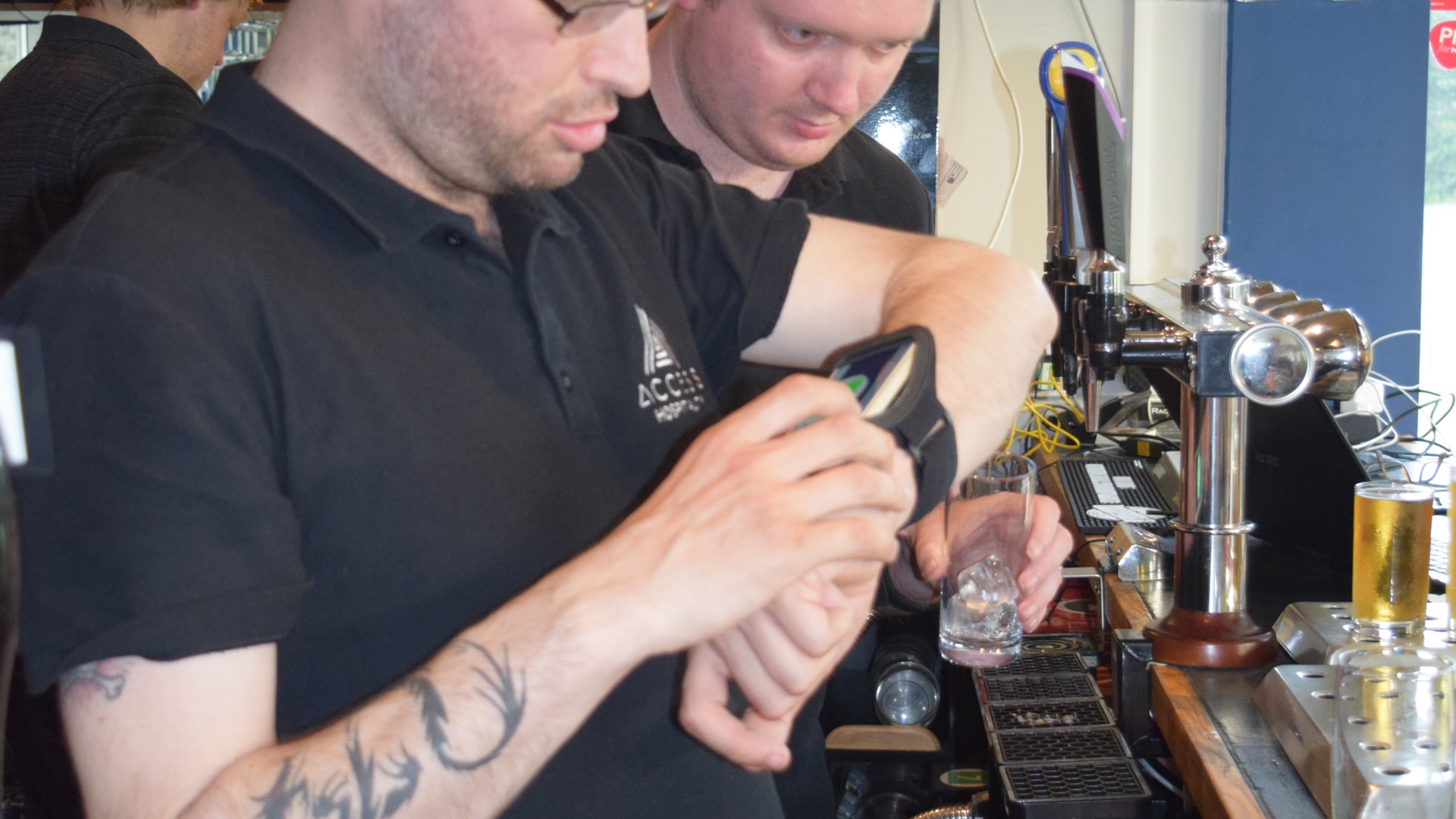 Magpies members behind a bar using smart devices around their wrists
